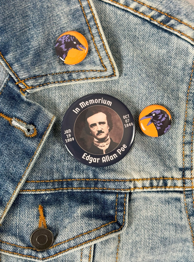 Edgar Allan Poe memorial pin flanked by two colorful raven pins mounted on a vintage denim jacket.